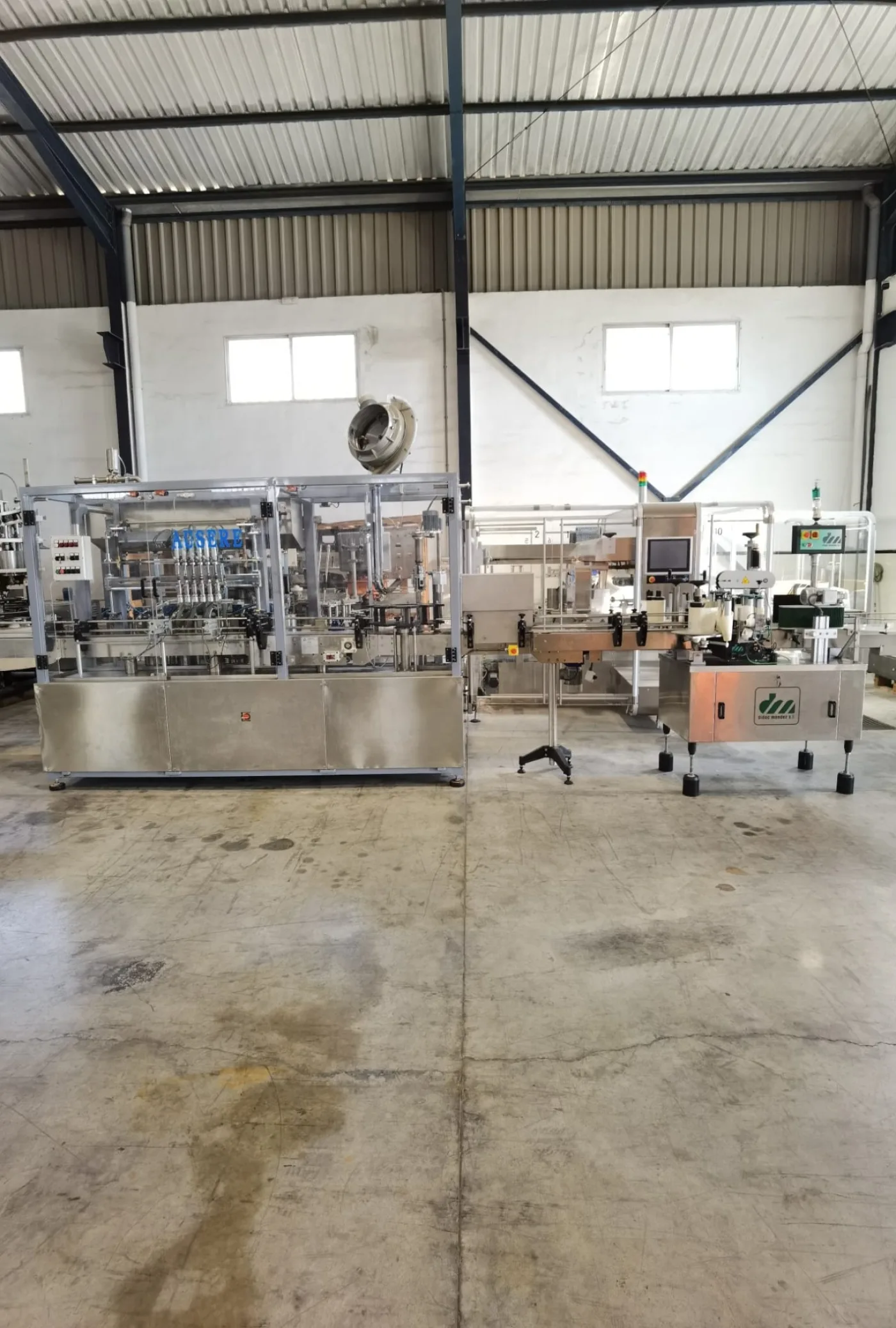 Linea de llenado y etiquetado con llenadora volumétrica Ausere de 6 pistones, taponadora Pilfer y etiquetadora autoadhesiva de 3 cabezales - 1